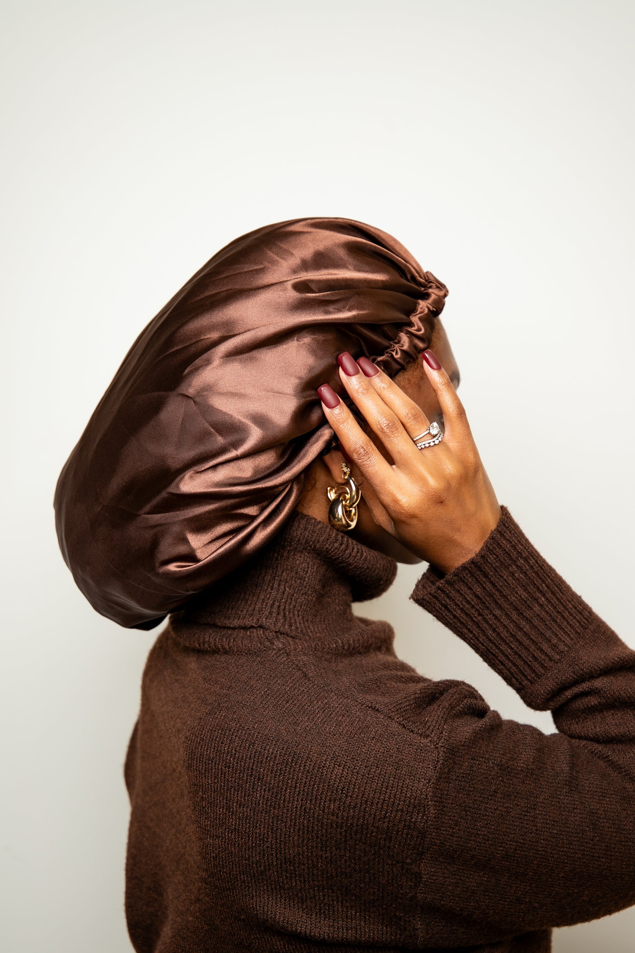 Person wearing a brown satin bonnet and matching sweater against a white background