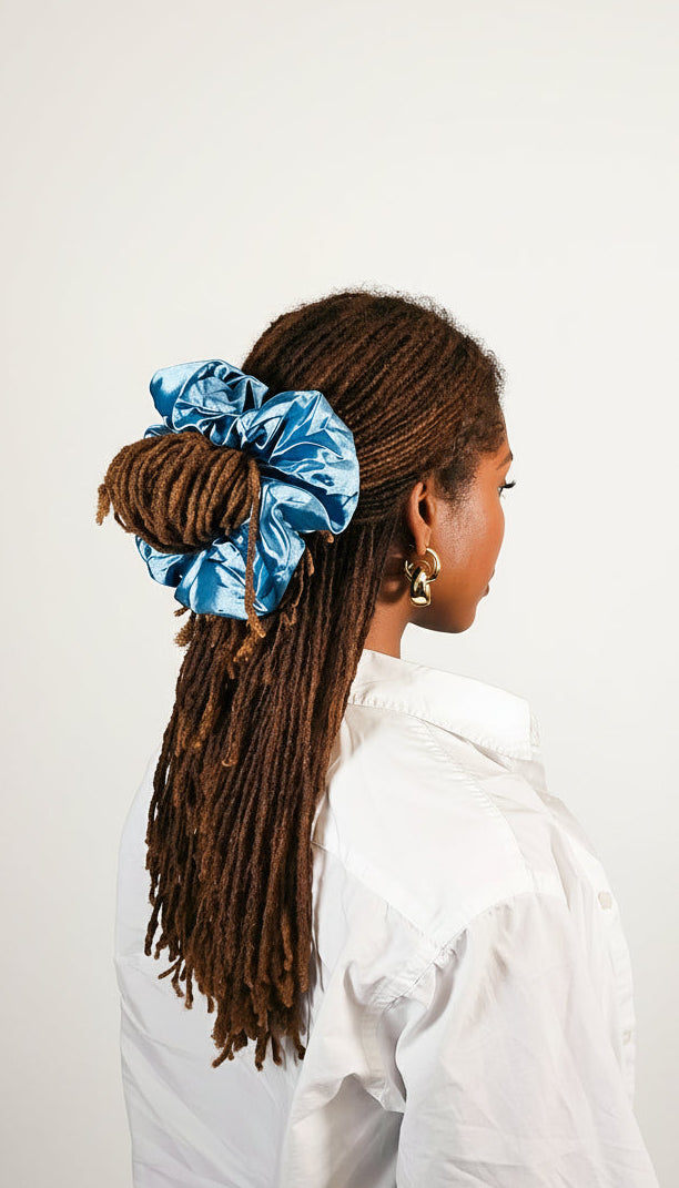 Person with long hair styled in a braid, wearing a blue scrunchie, on a white background